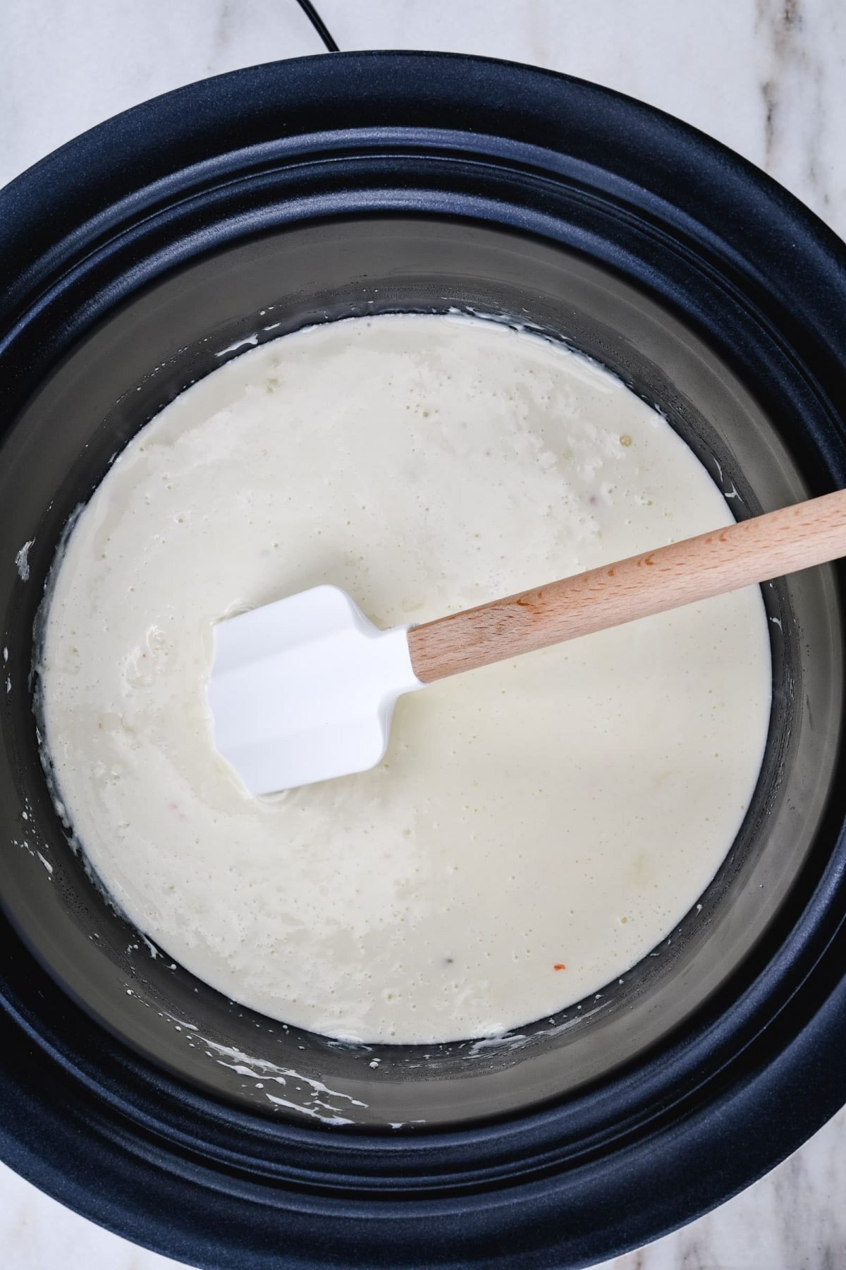Queso is stirred after all cheeses have melted and blended with milk.