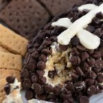 Photo of football shaped cookied dough dip with crackers on a white platter.