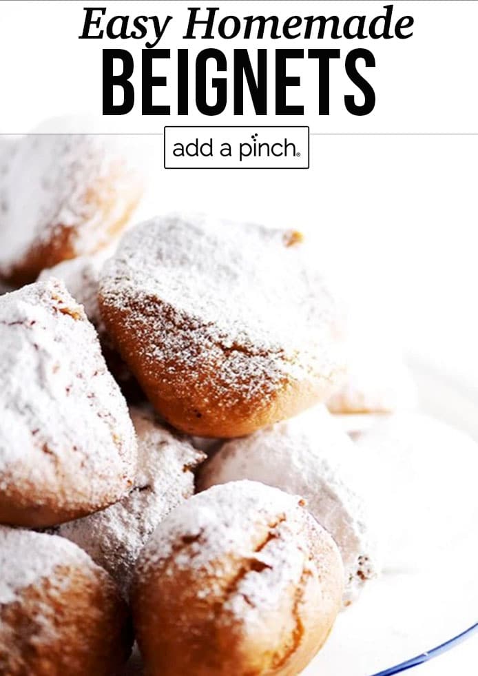 Plate of golden beignets dusted with powdered sugar - with text - addapinch.com