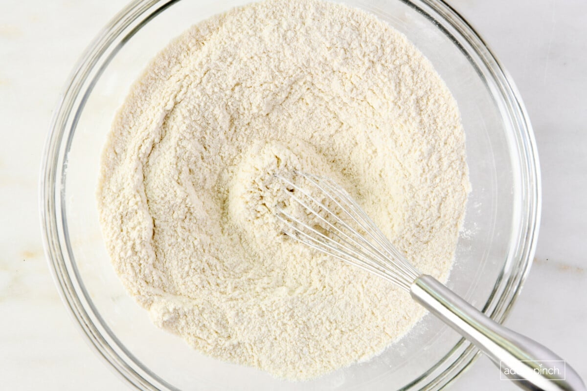 Flour mixture in a glass mixing bowl with a whisk.