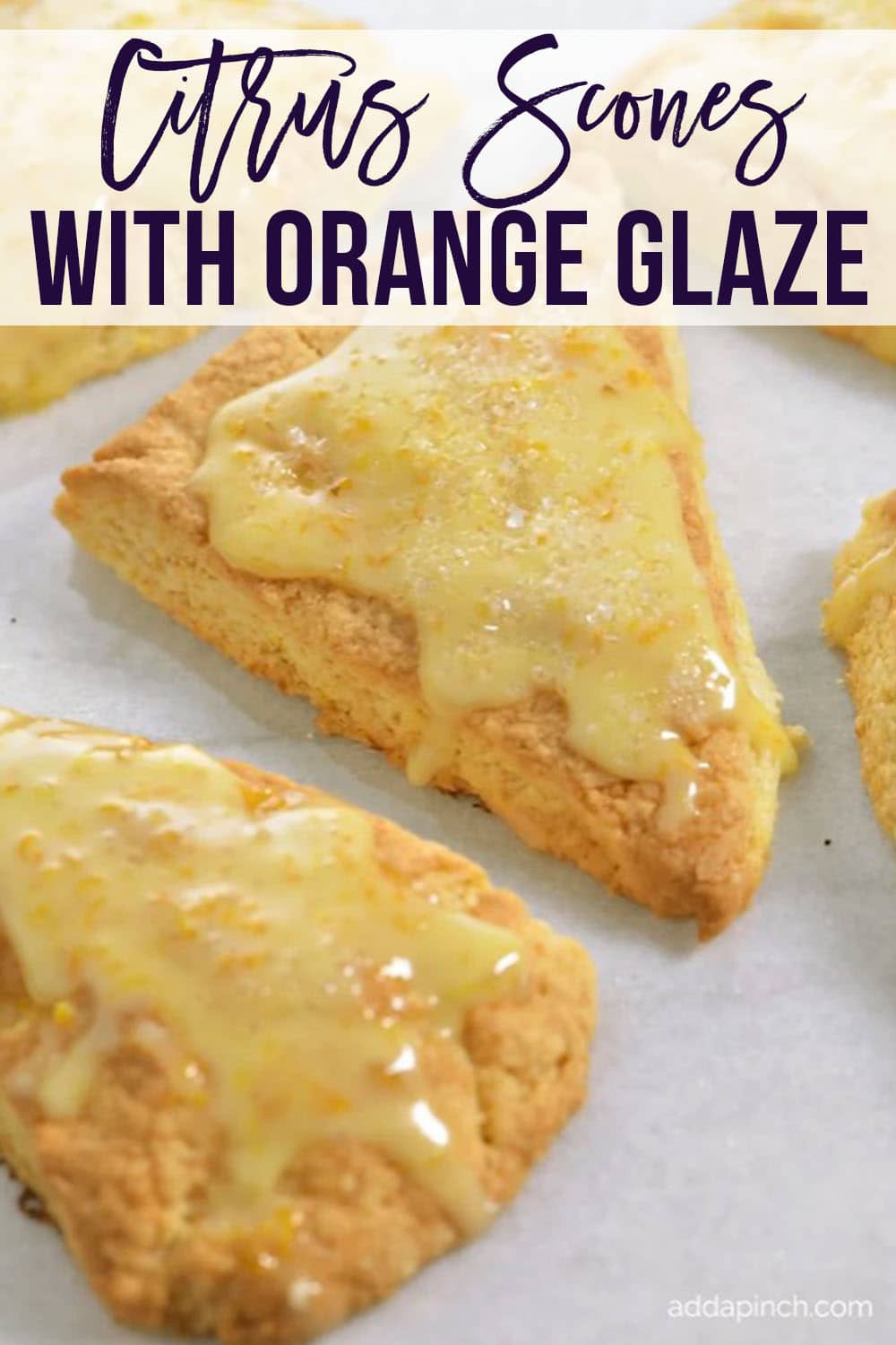 Baking pan covered in parchment with scones covered in orange glaze -with text - addapinch.com