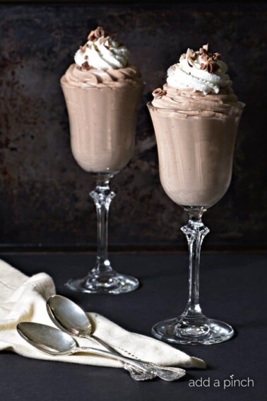 Photo of chocolate mousse in 2 glasses on black background.