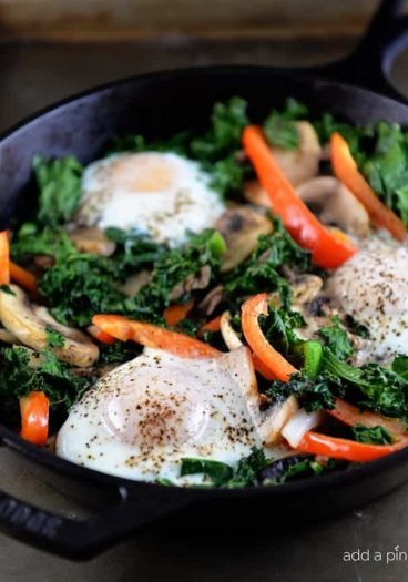 This kale breakfast skillet recipe is packed with flavor and ready in minutes! Made with kale, mushrooms, onions, peppers, and topped with eggs. // addapinch.com