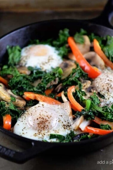 This kale breakfast skillet recipe is packed with flavor and ready in minutes! Made with kale, mushrooms, onions, peppers, and topped with eggs. // addapinch.com