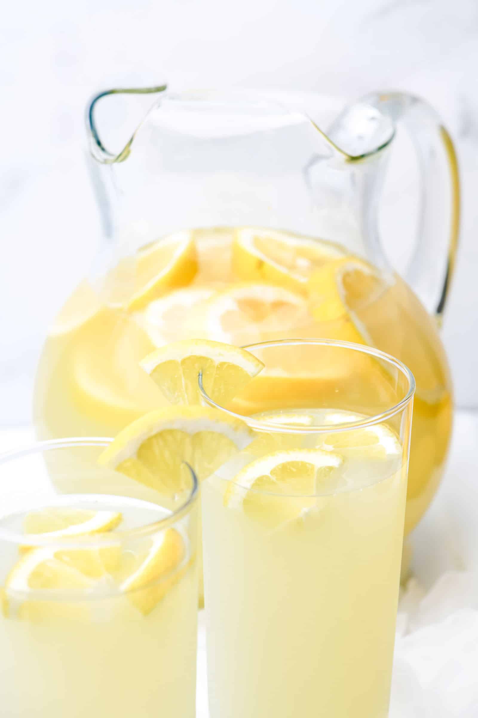 Lemonade. Glass jug with lemonade and lemon slices on a white