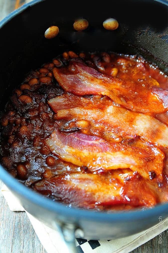 Baked beans topped with crispy slices of bacon in a cast iron dutch oven // addapinch.com