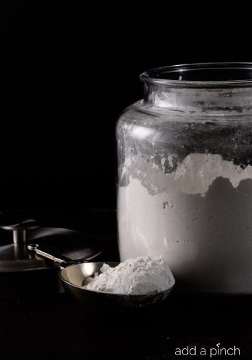 Flour in glass container with metal scoop // addapinch.com