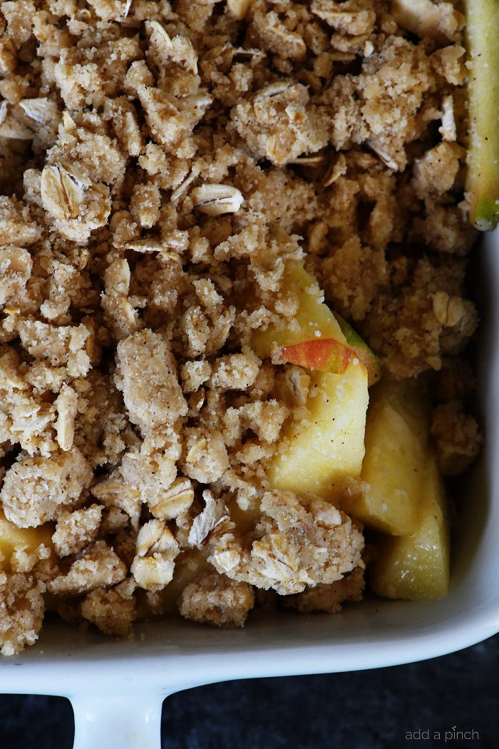 Apple Crisp recipe full of apples, spices and topped with streusel topping is assembled in baking dish and ready to bake - addapinch.com