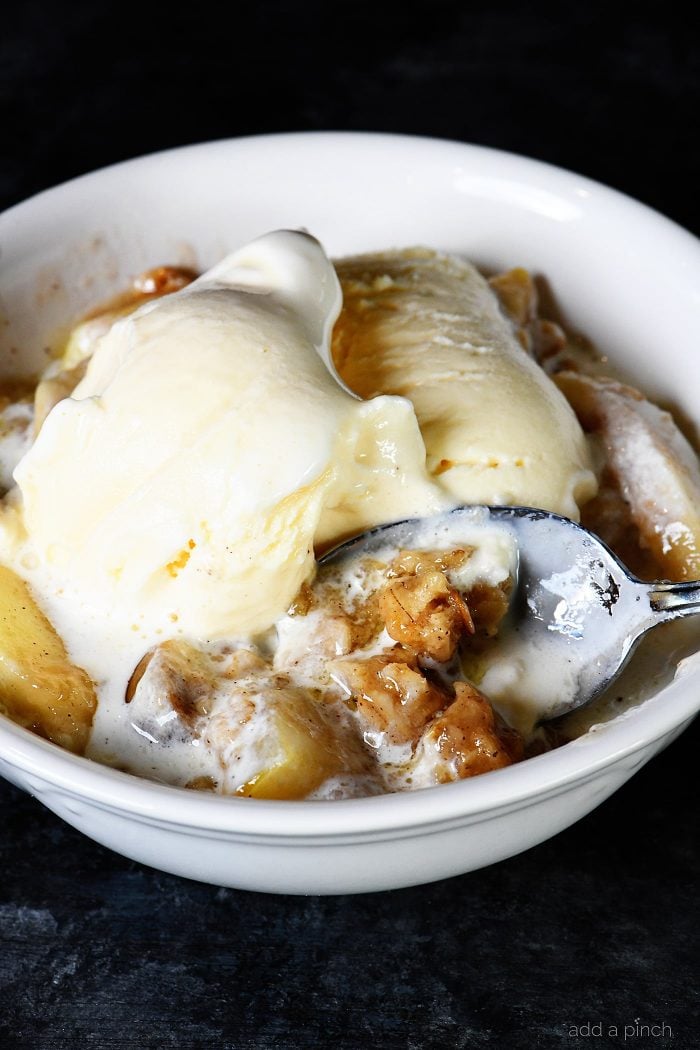 Bowl of Apple Crisp topped with vanilla ice cream.