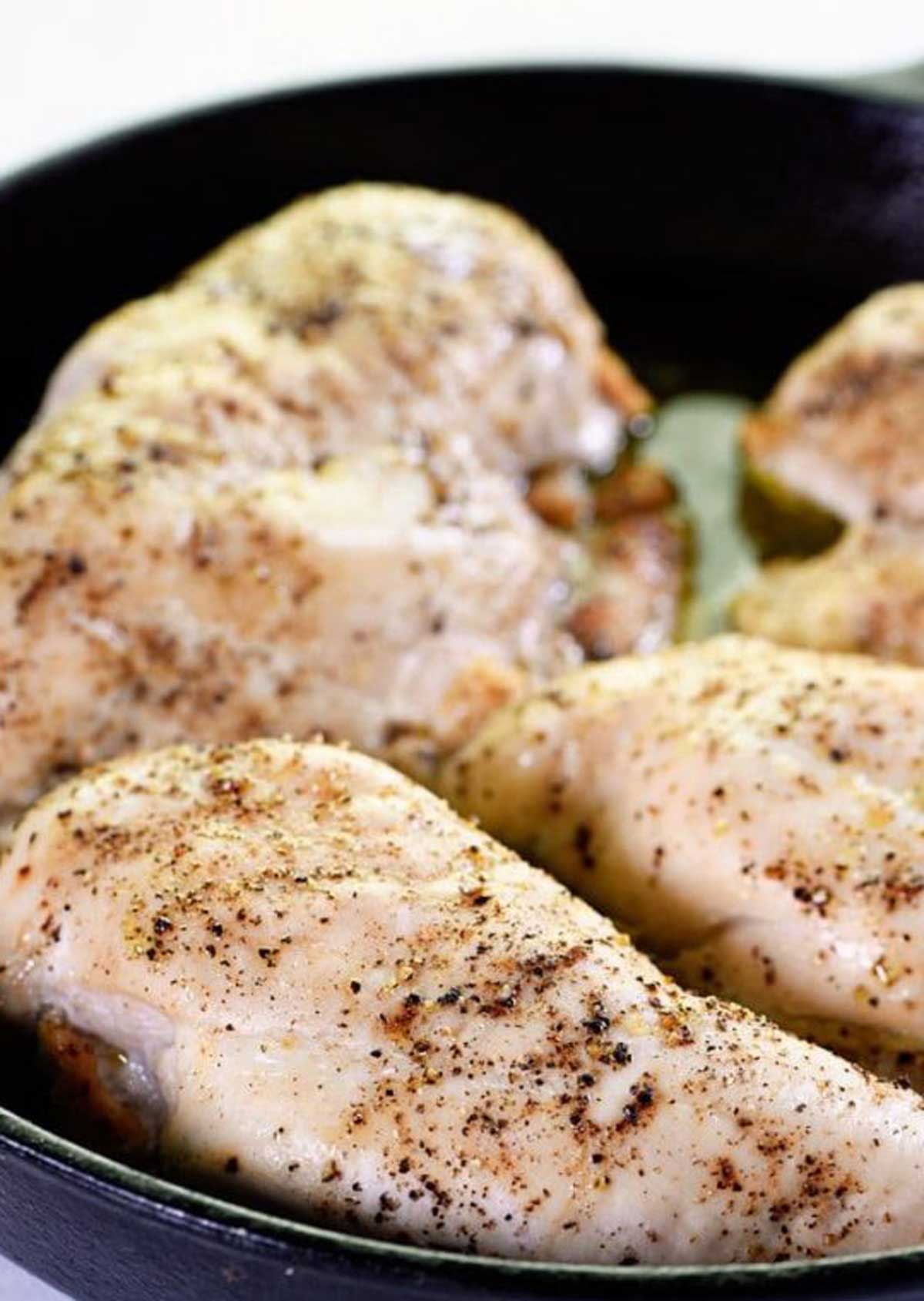 Cooked chicken seasoned and cooling in a black dish.
