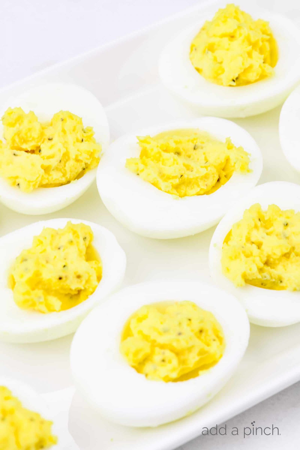 Closeup of deviled eggs on a white platter.