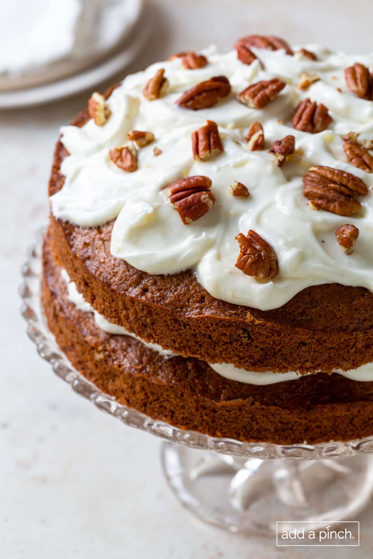 Photo of carrot cake with cream cheese frosting and pecans.