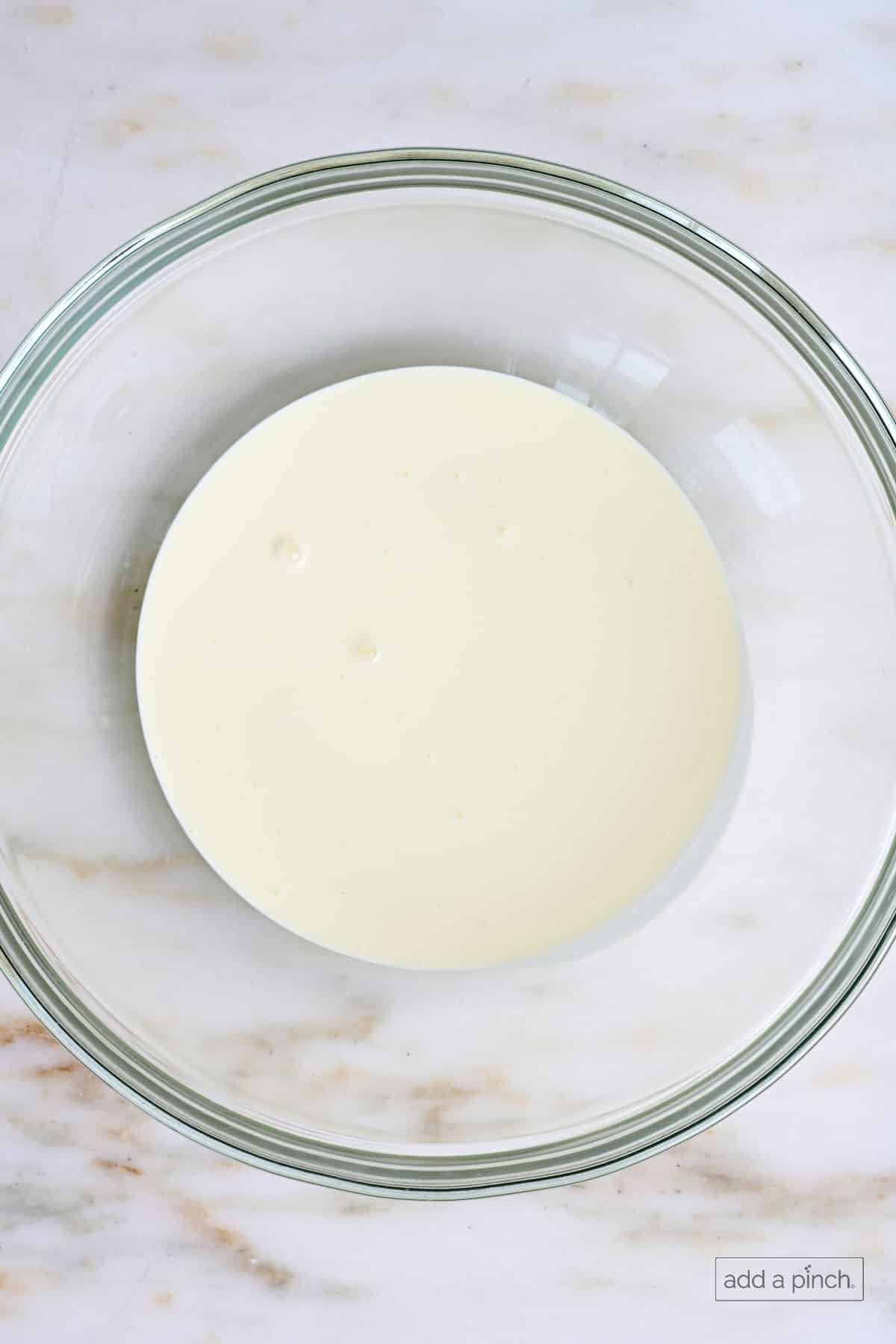 Heavy whipping cream in a glass mixing bowl.