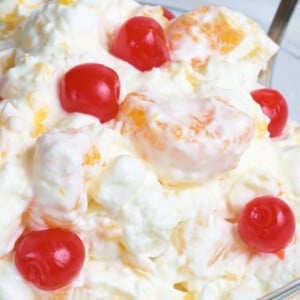 Ambrosia salad with cherries in a clear glass bowl.