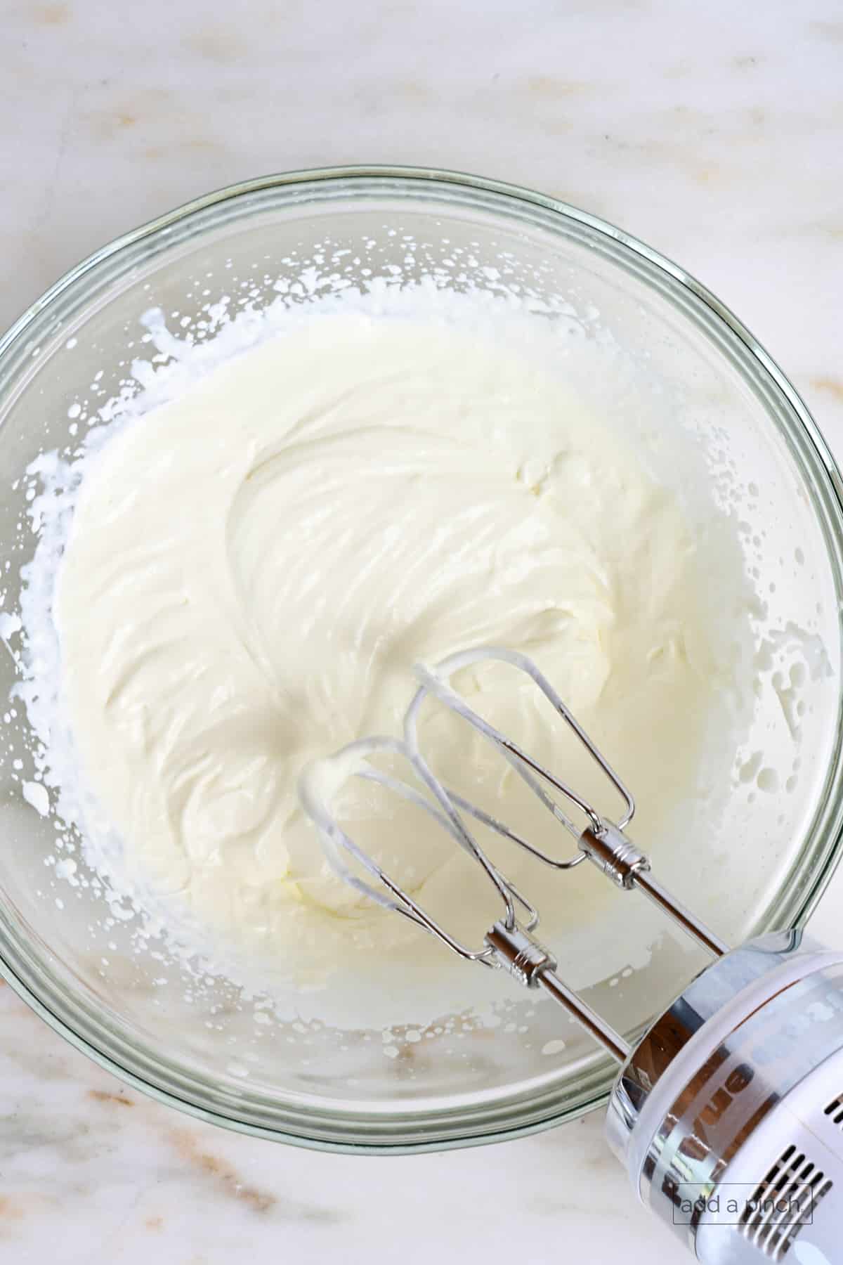 Lightly whipped heavy cream in a glass mixing bowl.