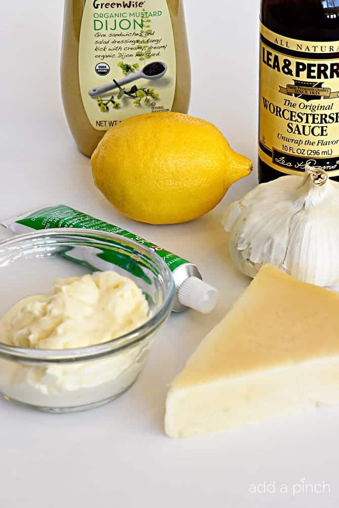 Ingredients to make homemade caesar dressing are gathered on a white countertop.