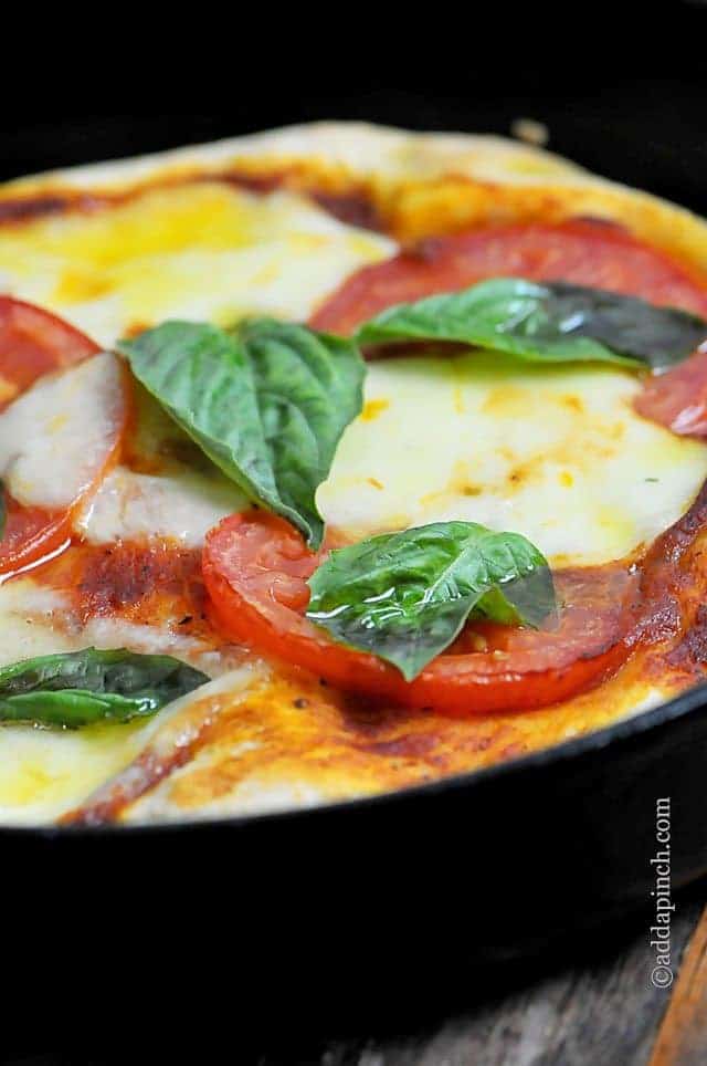 Deep dish pizza covered in tomatoes, basil and cheese //addapinch.com