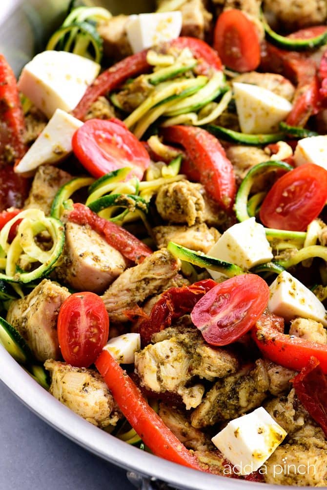 One Pan Pesto Chicken Recipe - This One Pan Pesto Chicken recipe makes a quick and easy answer to what's for supper? Made with chicken, pesto, peppers, tomatoes, zucchini and mozzarella, this will easily become a favorite! // addapinch.com