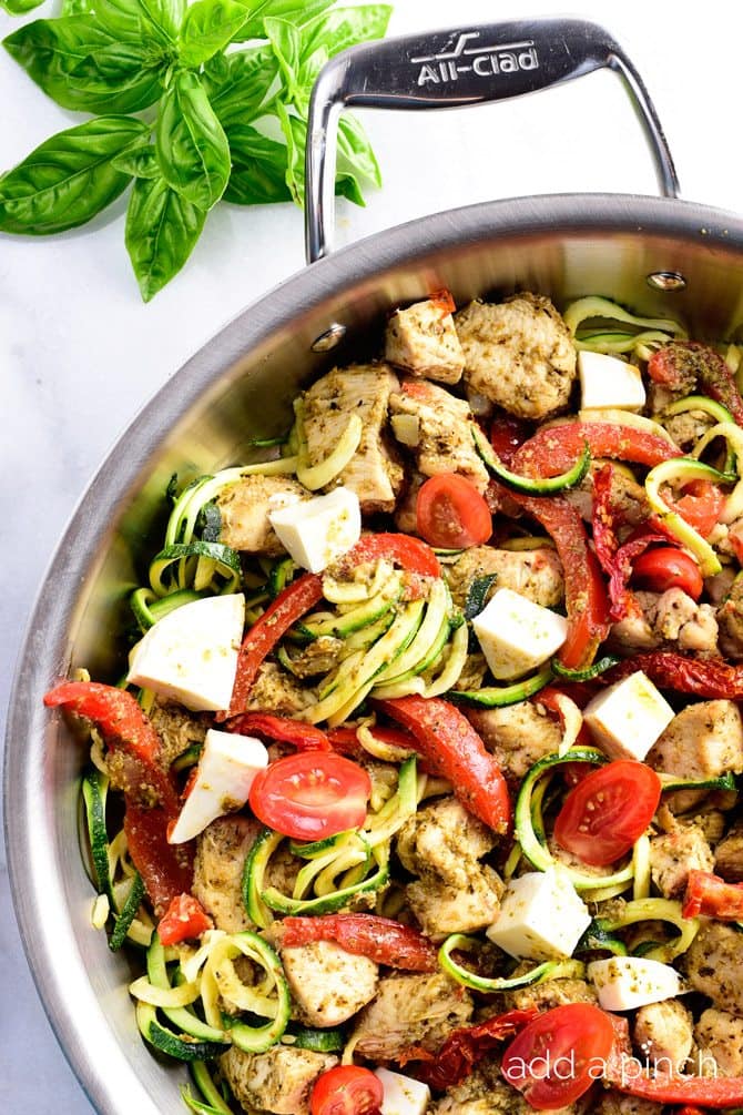 One Pan Pesto Chicken Recipe - This One Pan Pesto Chicken recipe makes a quick and easy answer to what's for supper? Made with chicken, pesto, peppers, tomatoes, zucchini and mozzarella, this will easily become a favorite! // addapinch.com