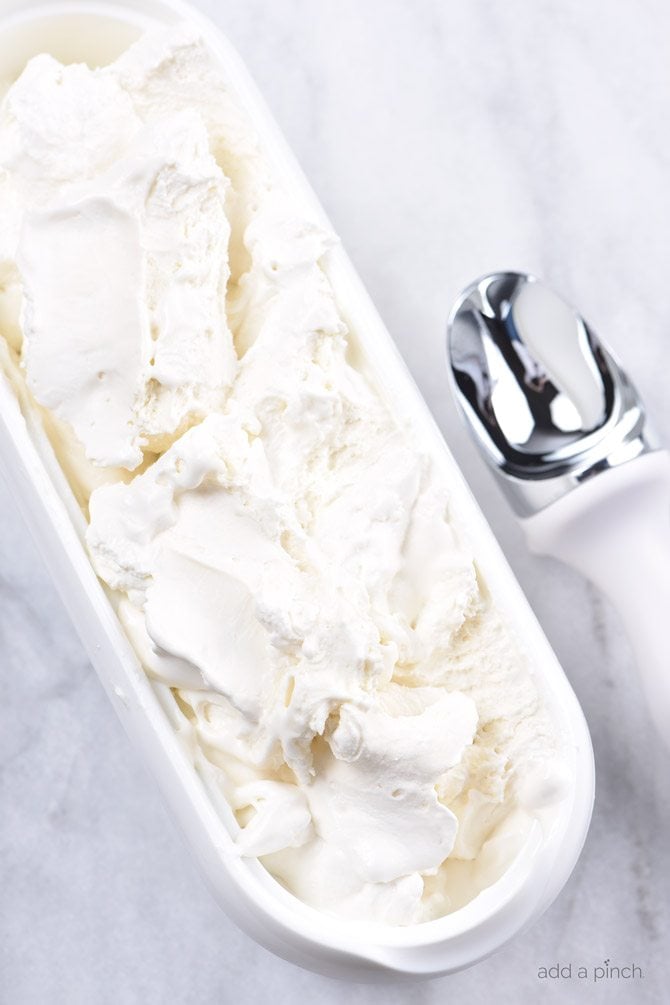White oblong tub of ice cream beside white and metal ice cream scoop, set on marble counter // addapinch.com