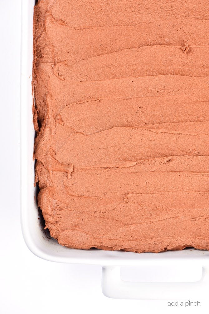 Overhead photo of chocolate cake with chocolate buttercream in a 9x13 white baking dish.