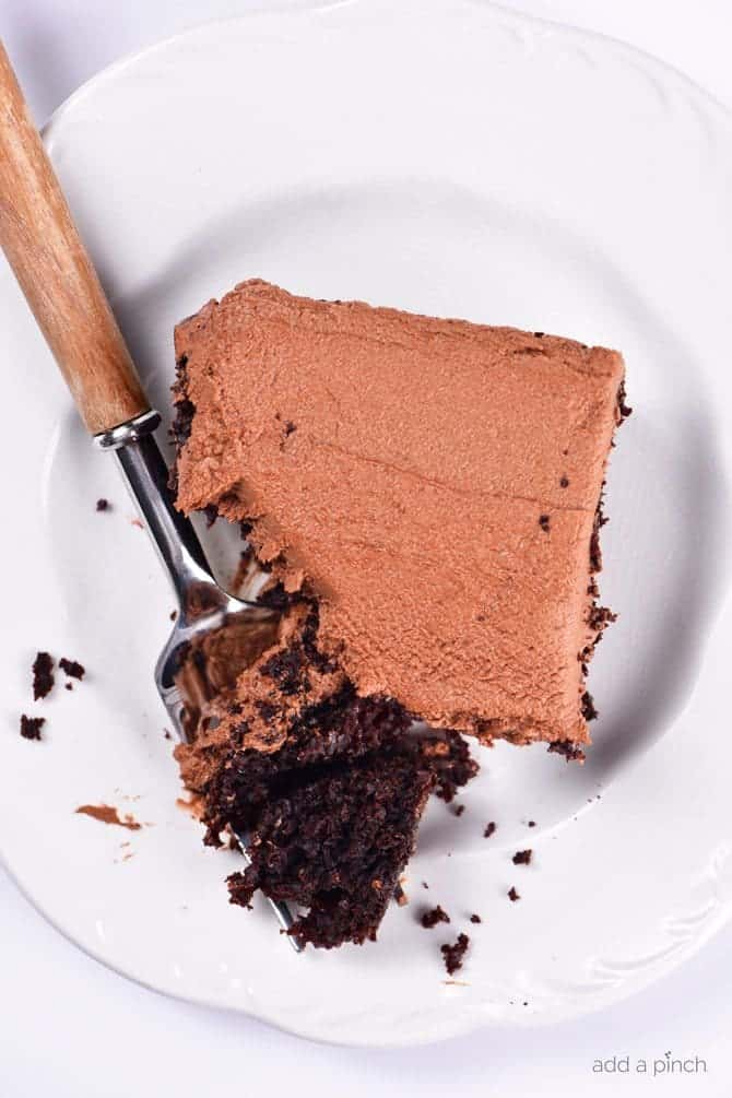 Square slice of chocolate cake with chocolate frosting with a bite on a fork, served on a white plate // addapinch.com