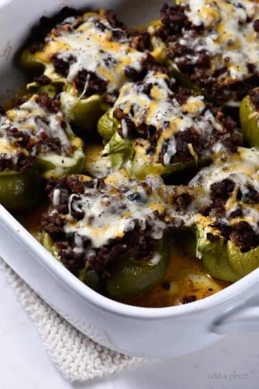White baking dish with bell peppers stuffed with cheesy black bean chili.