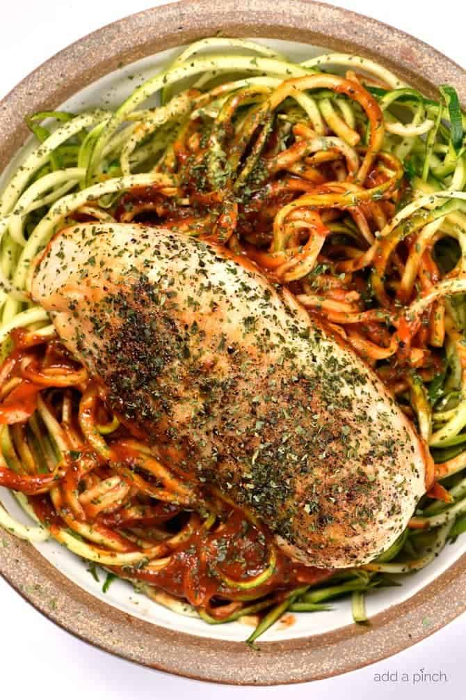 Basil topped chicken breast with sauce atop zucchini noodles