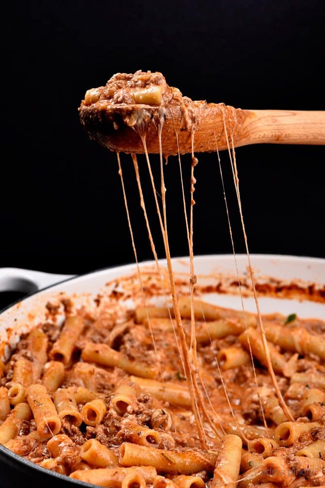 Skillet Beef Ziti with large cheese pull on wooden spoon -addapinch.com