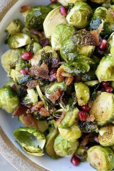 Roasted Brussels Sprouts with Pomegranate and Bacon Recipe - Roasted Brussels Sprouts with Pomegranate and Bacon make a delicious side dish! The brussels sprouts are roasted and then drizzled with maple syrup and balsamic vinegar and then tossed with crispy bacon and pomegranate! // addapinch.com