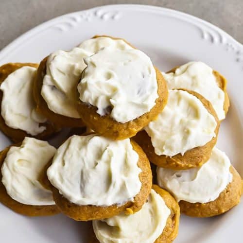 Photograph of pumpkin cookies topped with maple buttercream frosting on a white plate.