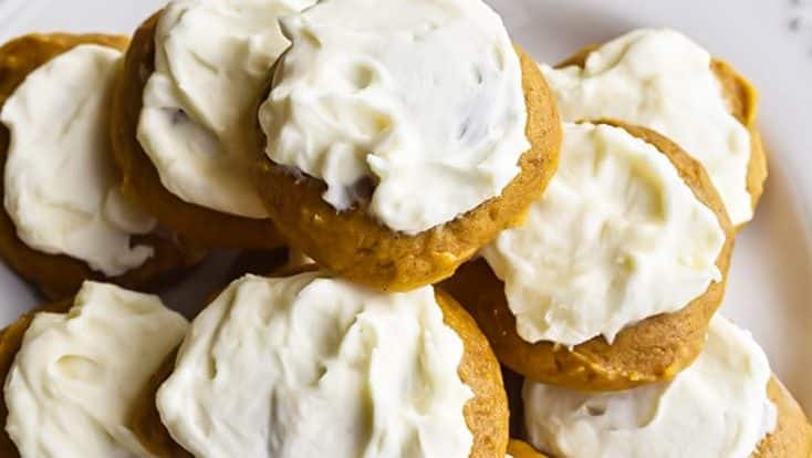 Photograph of pumpkin cookies topped with maple buttercream frosting on a white plate.