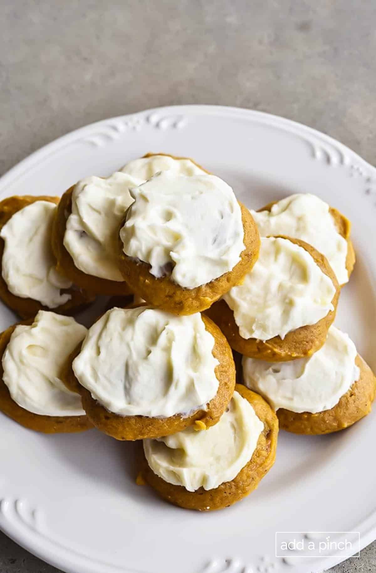 Photograph of pumpkin cookies topped with maple buttercream frosting on a white plate. 