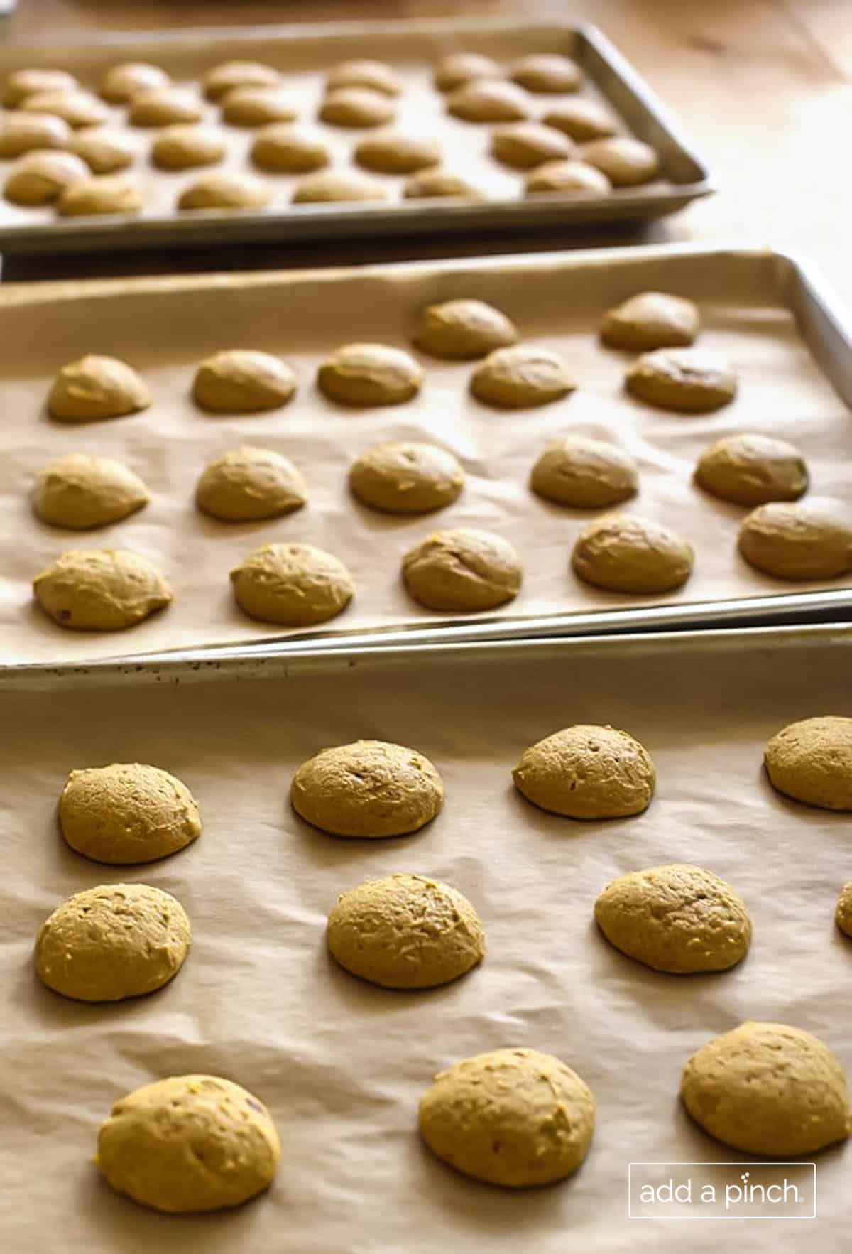 Image of baked pumpkin cookies on a baking sheet lined with payment paper. 