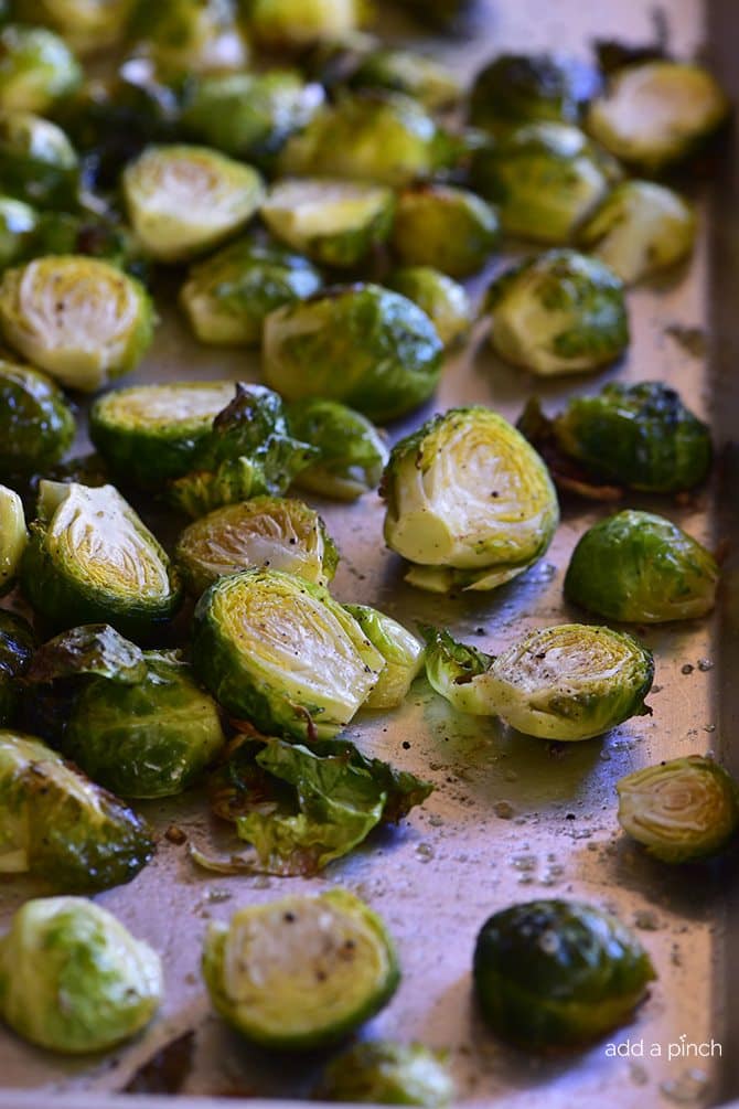 Brussels Sprouts cut in half and sprinkled with pepper - on pan ready to roast in oven. // addapinch.com