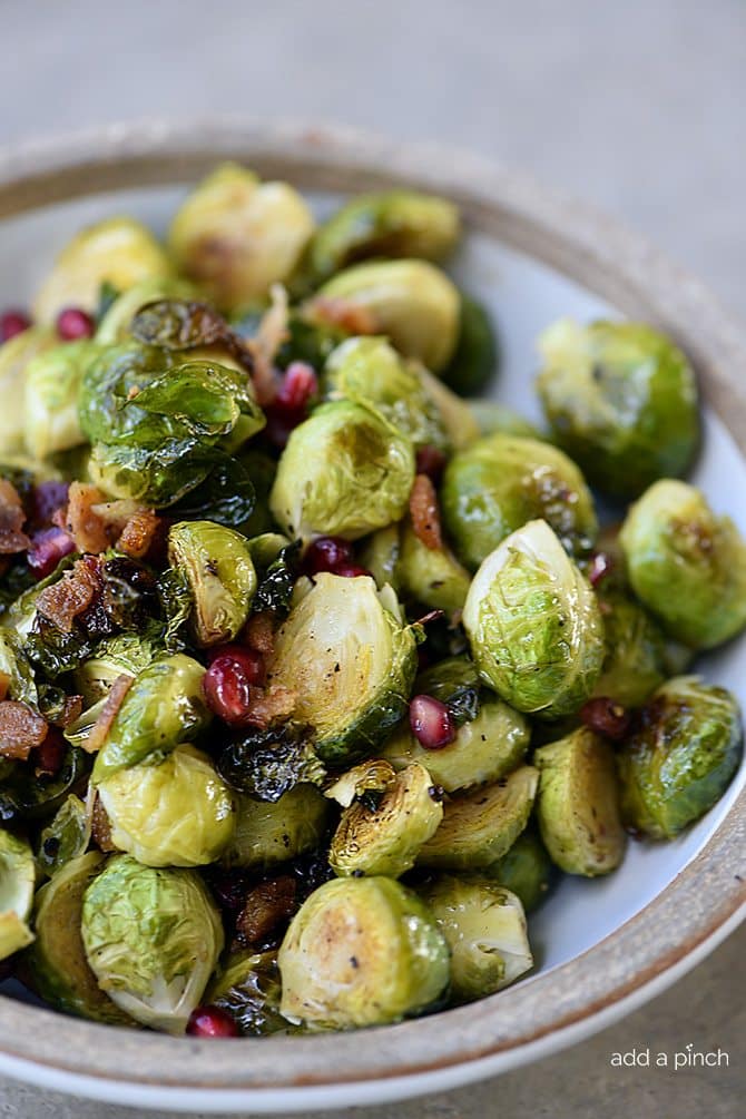 Roasted Brussels Sprouts with Pomegranate and Bacon Recipe - Roasted Brussels Sprouts with Pomegranate and Bacon make a delicious side dish! The brussels sprouts are roasted and then drizzled with maple syrup and balsamic vinegar and then tossed with crispy bacon and pomegranate! // addapinch.com