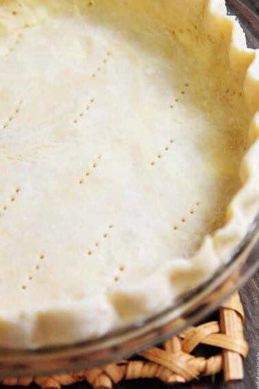 Unbaked pie crust pricked with a fork and fluted along the edges in a glass pie plate.