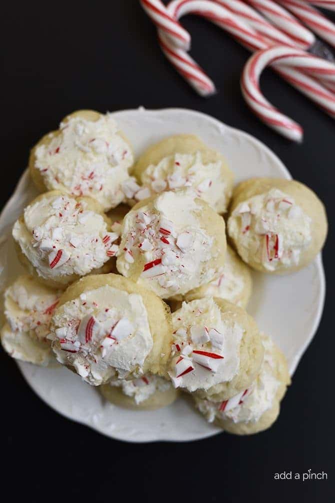 White plate of cookies topped with white frosting and crushed peppermint.