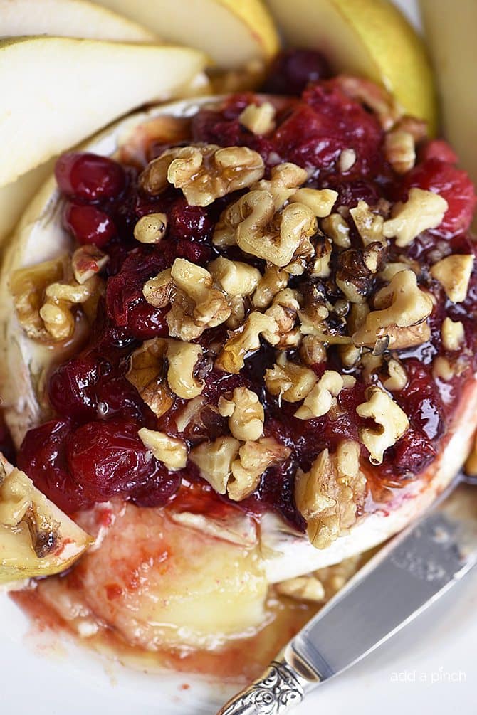Warm Brie with Honeyed Fruit Compote makes a beautiful, quick and easy appetizer. Made with a honeyed cranberry walnut fruit compote, this warm brie recipe is festive for the holidays! // addapinch.com