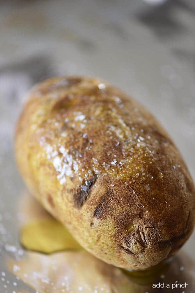 Perfect Baked Potato Recipe - The perfect baked potato recipe for a crispy, golden skin and a fluffy, tender inside. Learn how to make the best baked potatoes every time! // addapinch.com