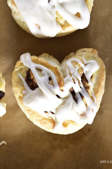 Overhead photo of iced cinnamon roll biscuits in heart shapes.