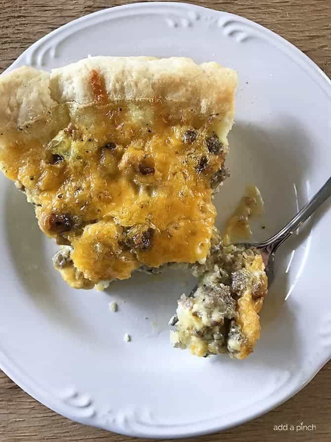 Slice of Sausage Cheddar Quiche on a white plate with fork // addapinch.com