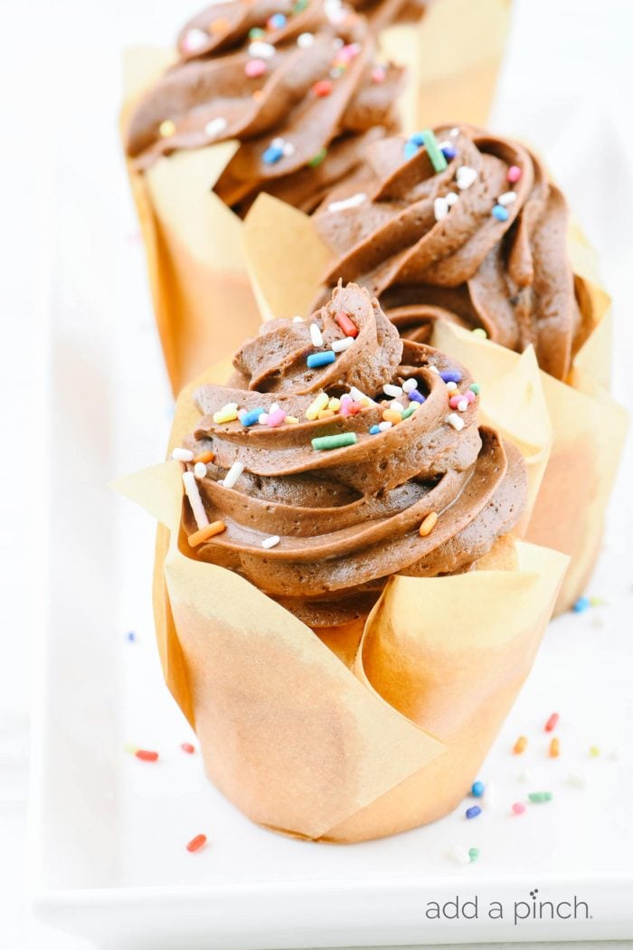 Vanilla cupcakes topped with swirls of chocolate buttercream frosting and sprinkles. 