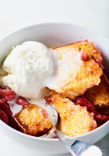 Easy strawberry cobbler topped with vanilla ice cream in a white bowl