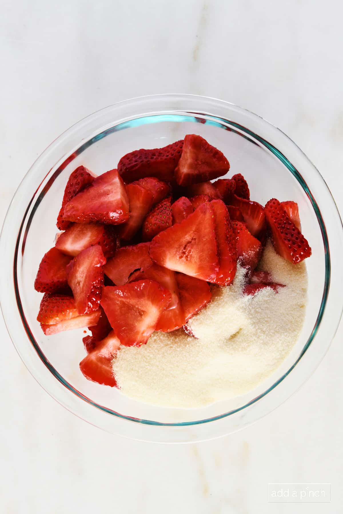 Strawberries and sugar in a glass bowl