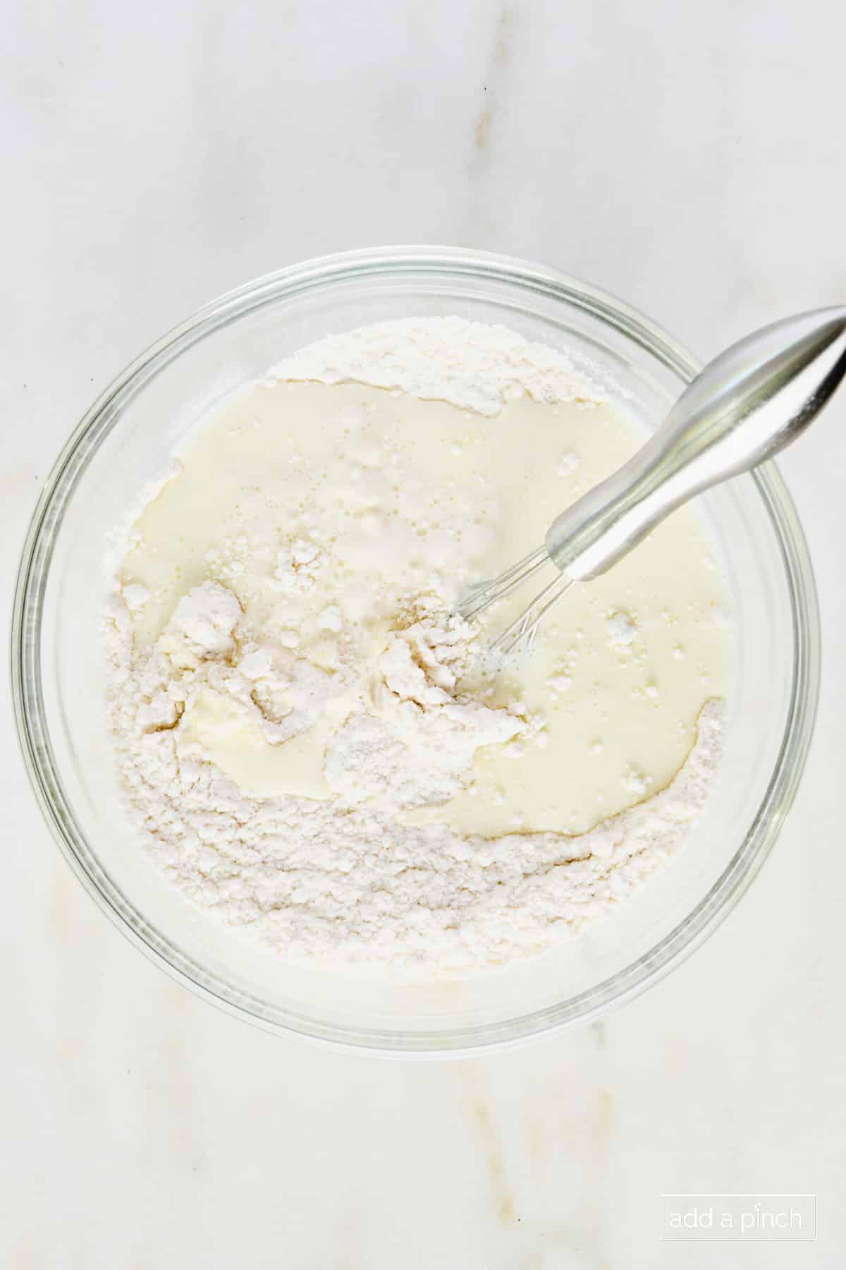 Flour mixture and milk in a glass bowl with a whisk