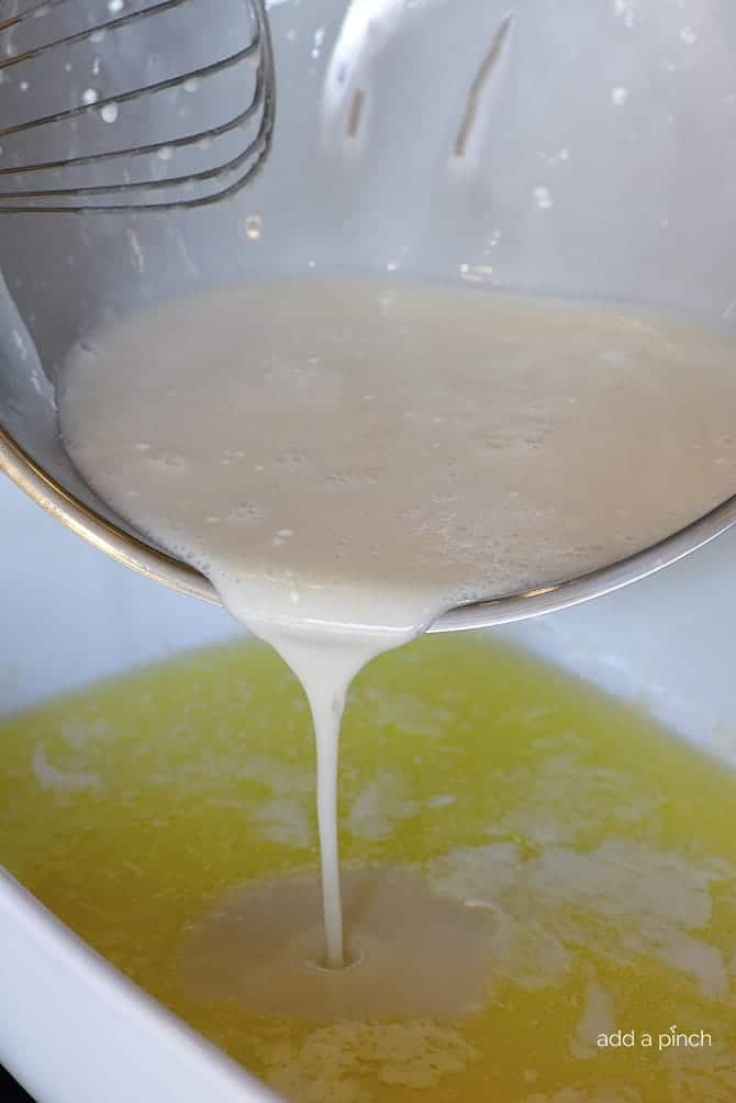 Batter being poured into baking dish of melted butter // addapinch.com
