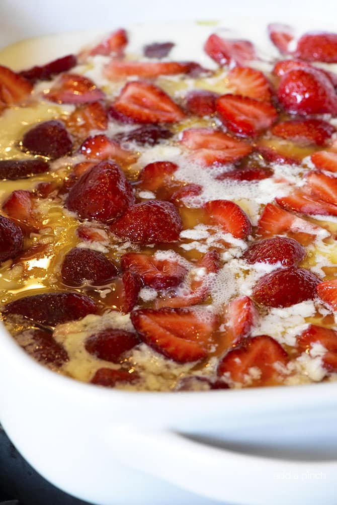  Strawberries added into baking dish of melted butter and cobbler batter // addapinch.com