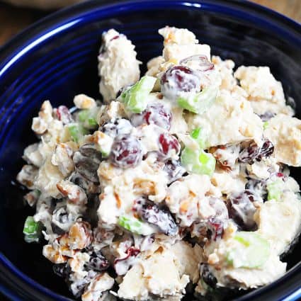 Photograph of chicken salad in a blue bowl on a dark counter.