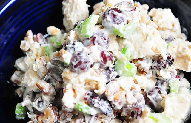 Photograph of chicken salad in a blue bowl on a dark counter.